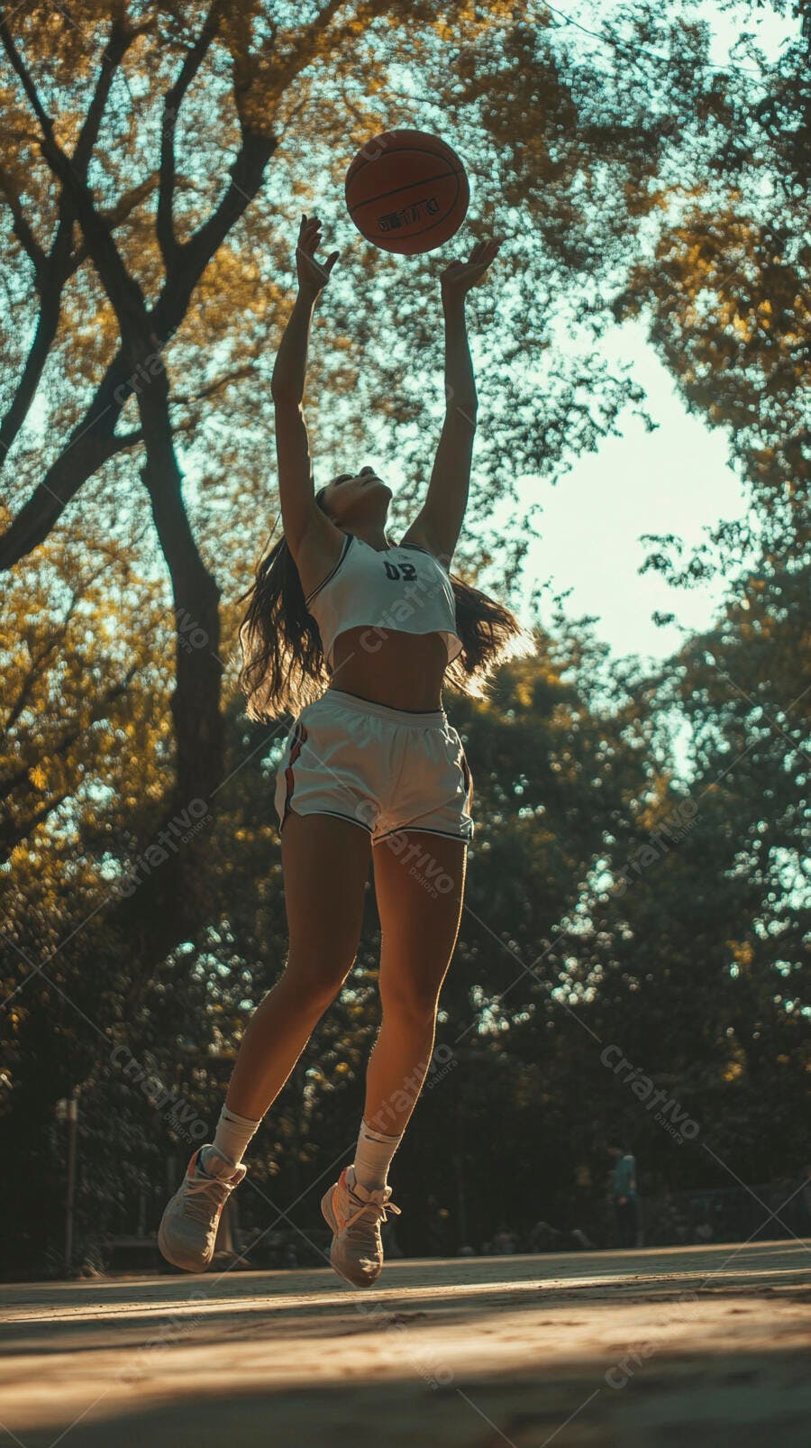 Jovem mulher atlética pulando para pegar bola de basquete ao ar livre