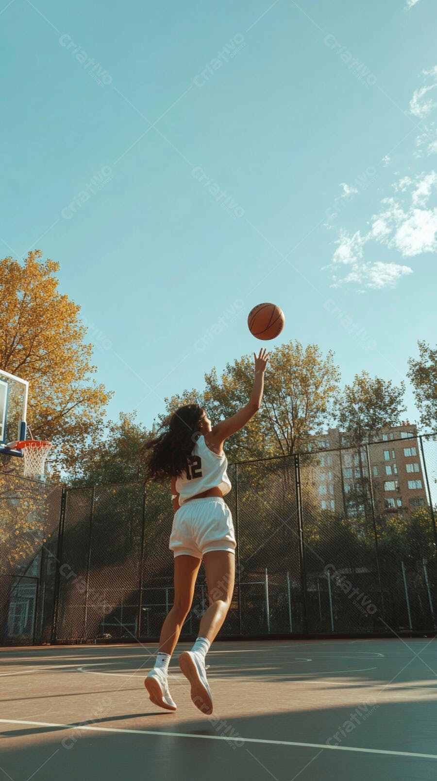Jovem mulher atleta jogando basquete em quadra ensolarada urbana