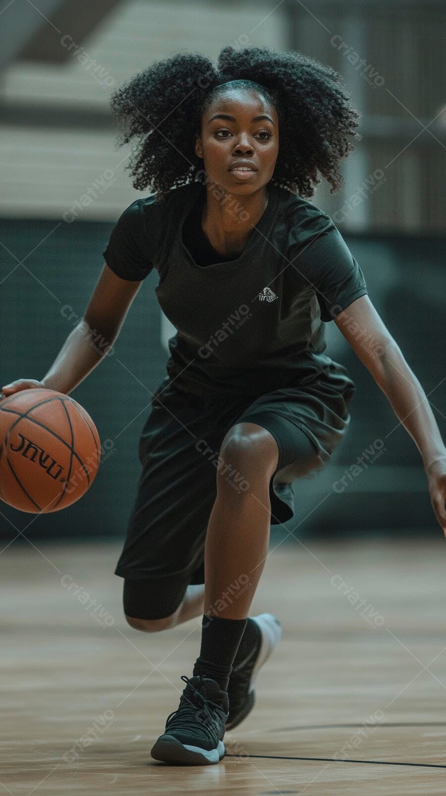 Mulher negra atlética driblando bola de basquete em quadra interna