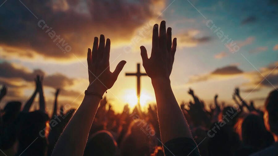 Mãos de pessoas erguidas em adoração com cruz ao pôr do sol dourado