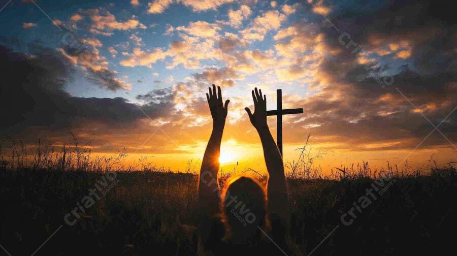 Pessoa com braços erguidos em oração diante de cruz ao pôr do sol laranja