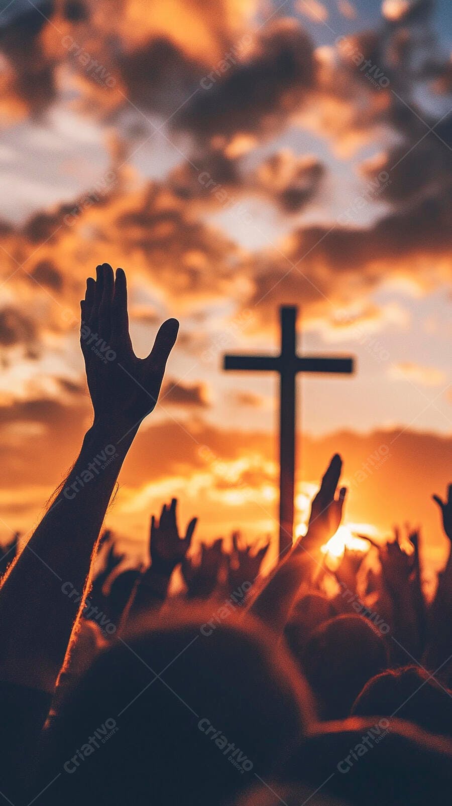 Pessoas com mãos erguidas adorando cruz cristã ao pôr do sol laranja