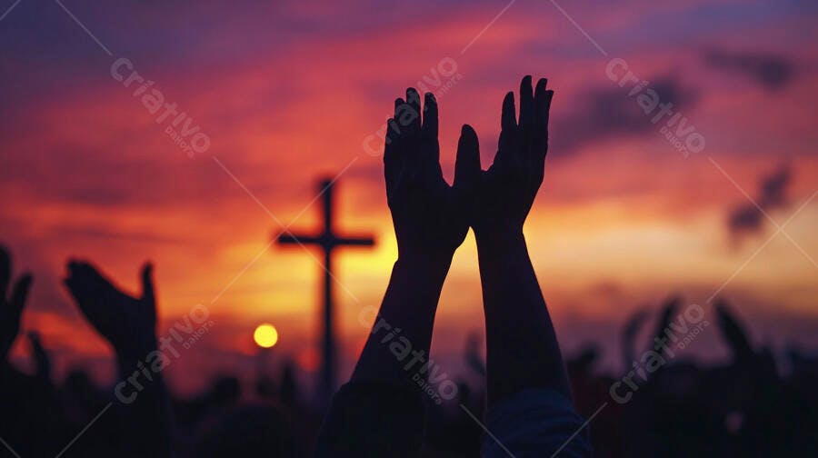 Mãos erguidas em adoração com cruz cristã ao pôr do sol alaranjado e roxo