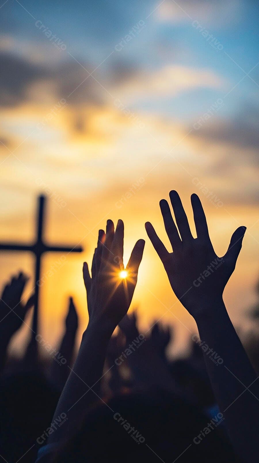 Mãos levantadas em oração ao pôr do sol com cruz ao fundo