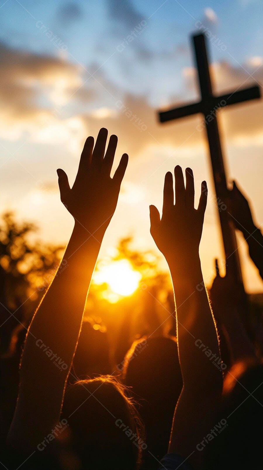 Mãos erguidas em oração no por do sol com cruz e céu alaranjado