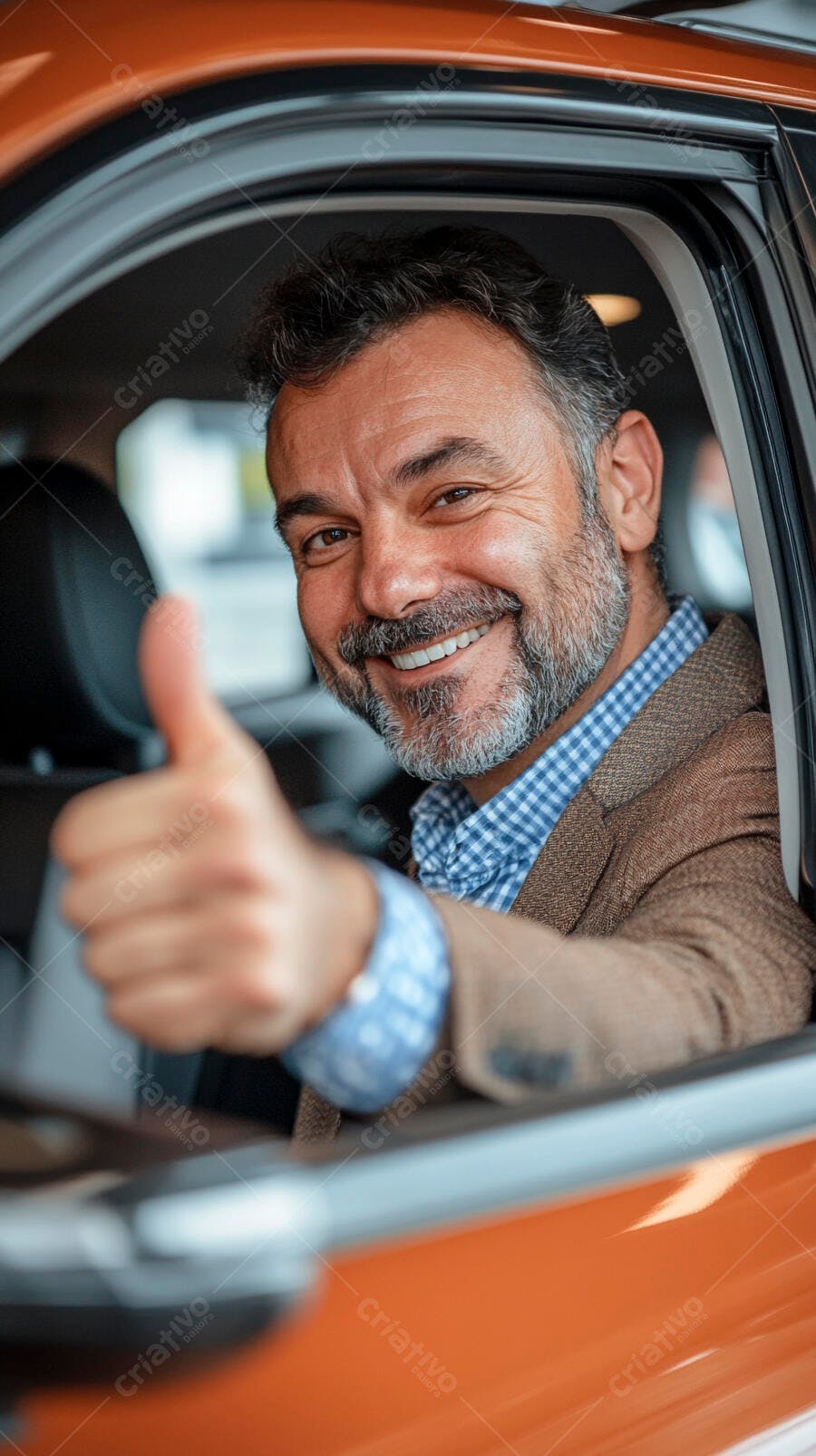 Homem sorridente de meia-idade com polegar para cima dentro de carro laranja novo