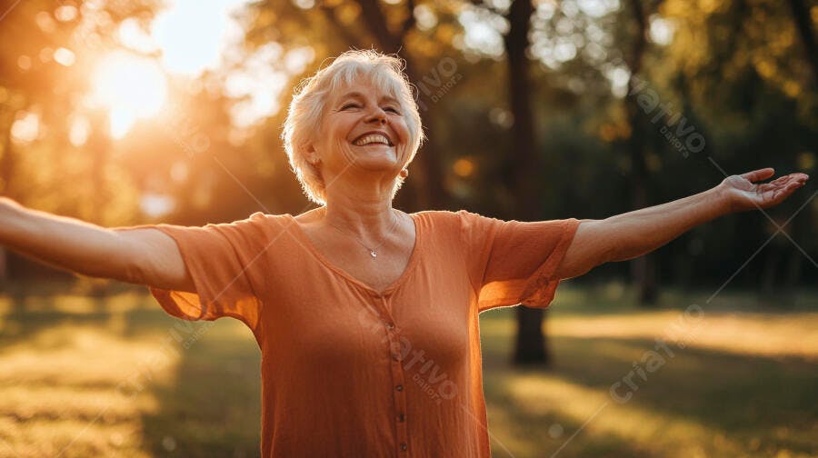 Mulher sênior feliz braços abertos em parque sob sol dourado