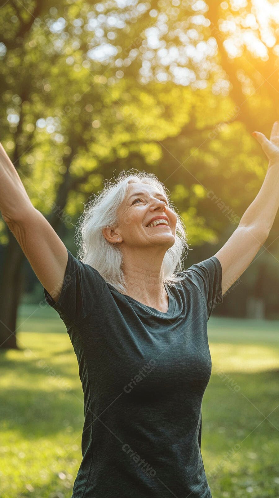 Mulher sênior de cabelos grisalhos sorrindo com braços abertos em um parque ensolarado