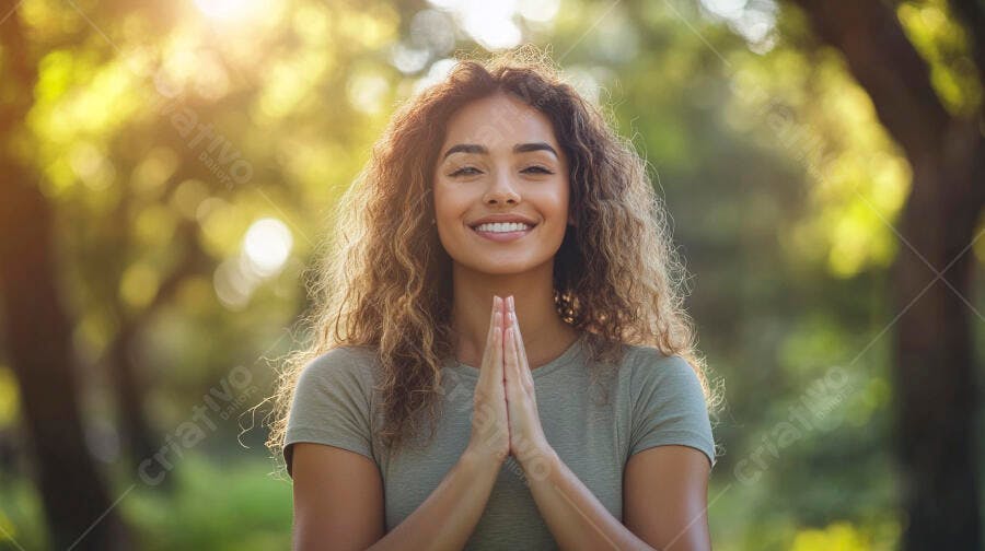 Mulher jovem sorrindo com mãos em oração em parque verde ensolarado