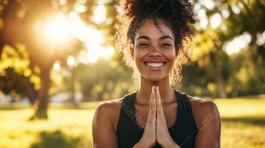 Mulher negra sorrindo em pose de yoga no parque ao pôr do sol