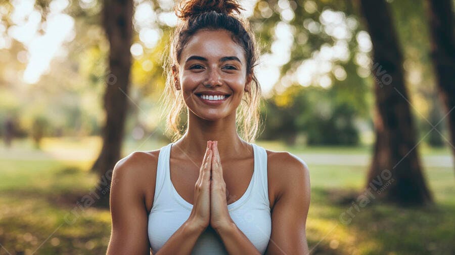 Mulher jovem morena sorrindo com mãos em prece no parque ensolarado