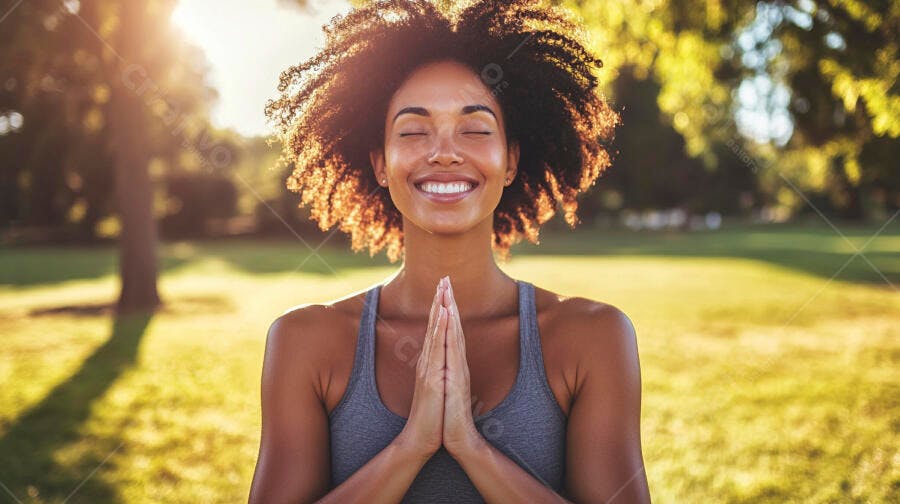 Mulher negra sorrindo meditando no parque ao pôr do sol dourado