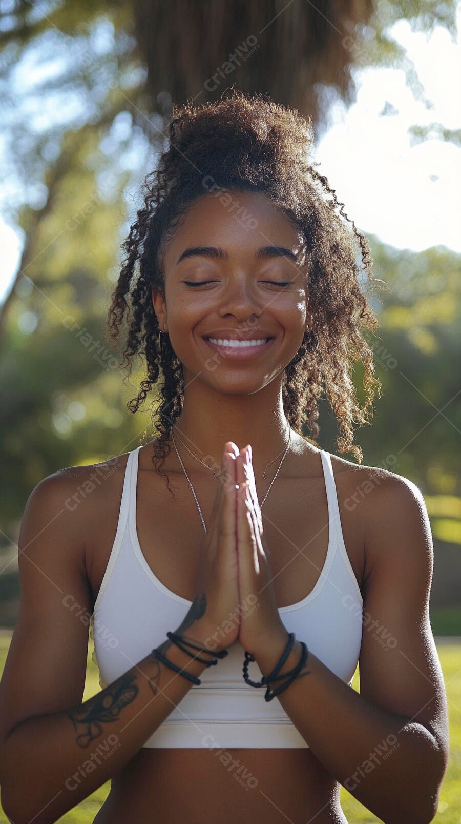 Mulher negra sorrindo meditando em pose de yoga no parque ensolarado