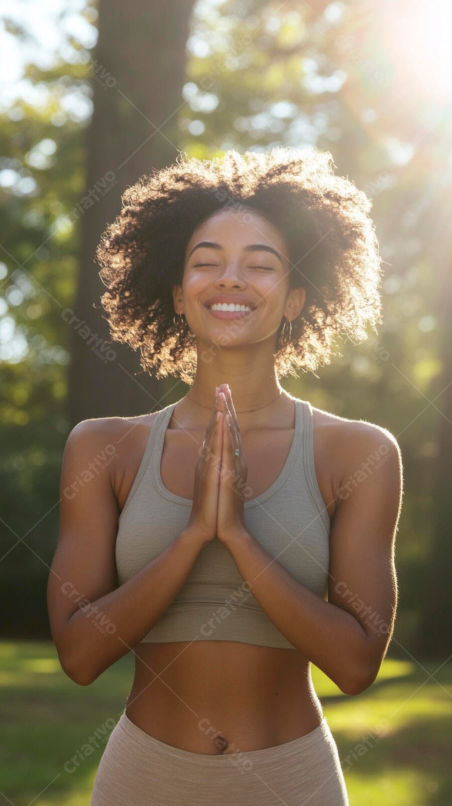 Mulher negra de cabelo cacheado meditando no parque ensolarado com sorriso
