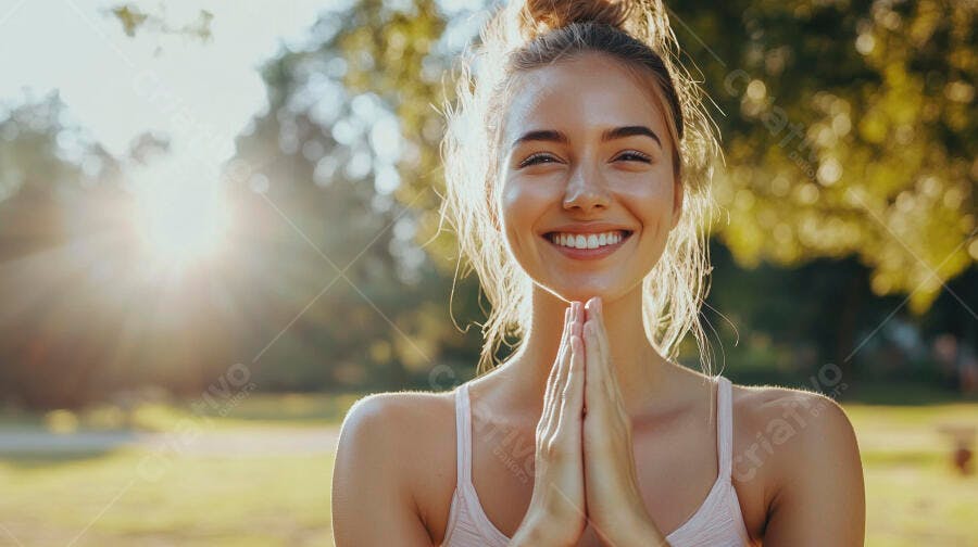 Mulher jovem sorrindo com mãos em namaste ao ar livre no parque ensolarado