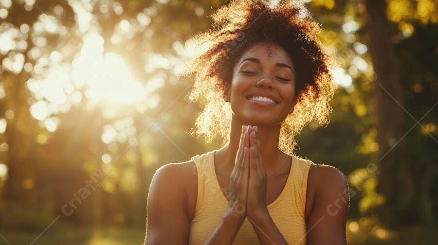 Mulher negra feliz meditando ao ar livre com luz dourada do sol