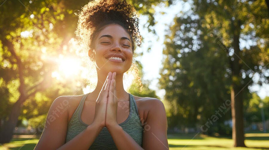 Mulher negra jovem sorrindo em pose de yoga no parque ao pôr do sol