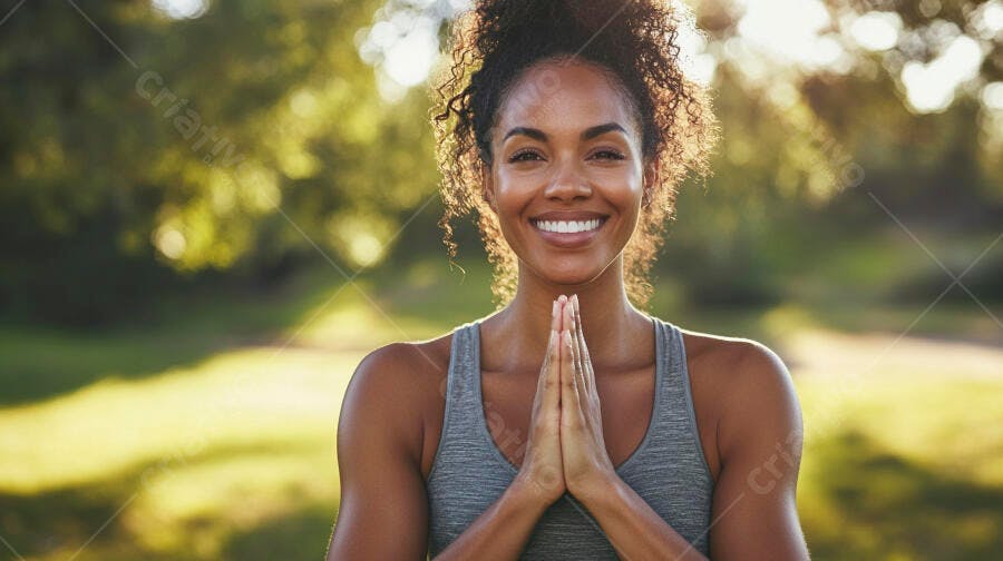 Mulher negra sorrindo em pose de yoga no parque com luz dourada