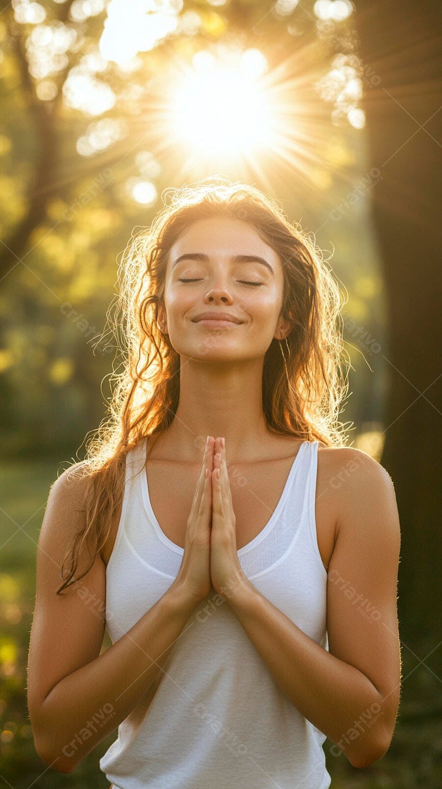 Mulher jovem meditando com as mãos unidas ao pôr do sol em um parque verde