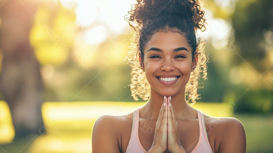Mulher negra sorrindo em pose de yoga ao ar livre com luz dourada
