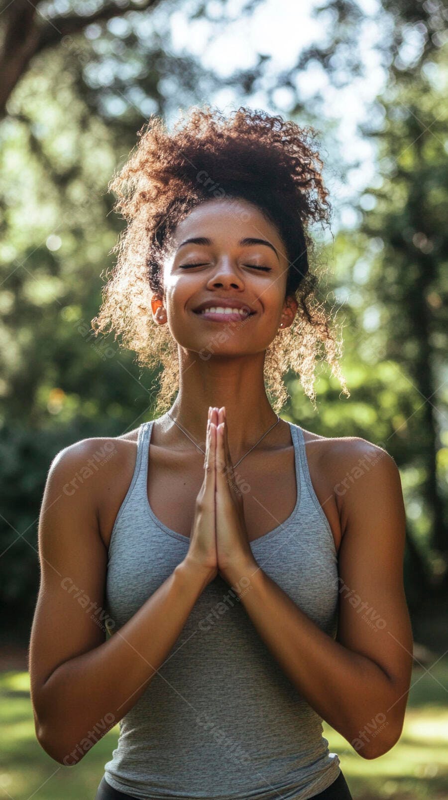 Mulher negra meditando sorrindo em pose de oração no parque com sol