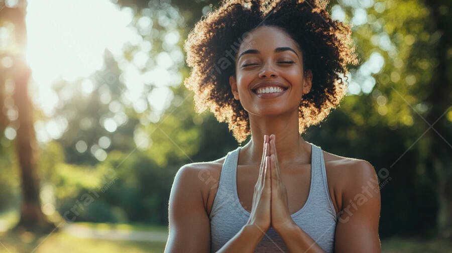 Mulher negra sorrindo meditando no parque sob luz do sol