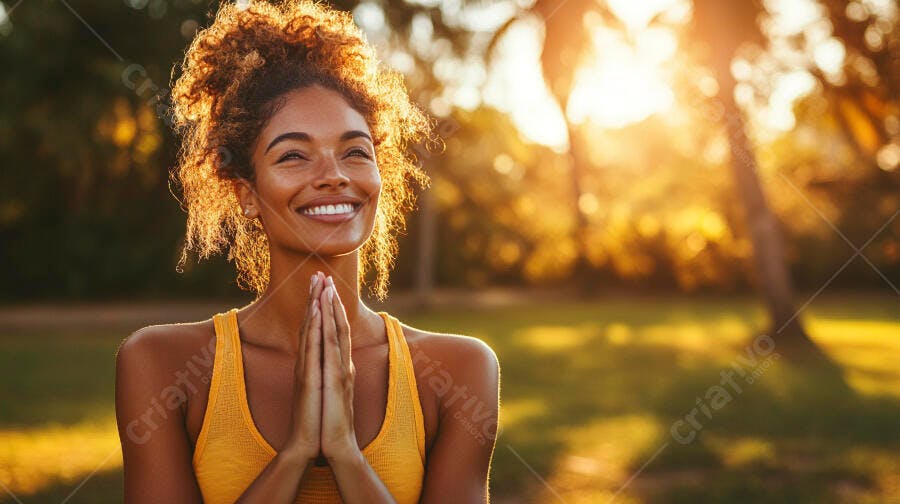 Mulher de pele escura sorrindo com cabelos cacheados em meditação ao pôr do sol