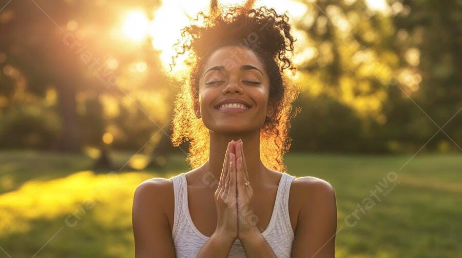 Mulher negra feliz orando no parque ao pôr do sol dourado