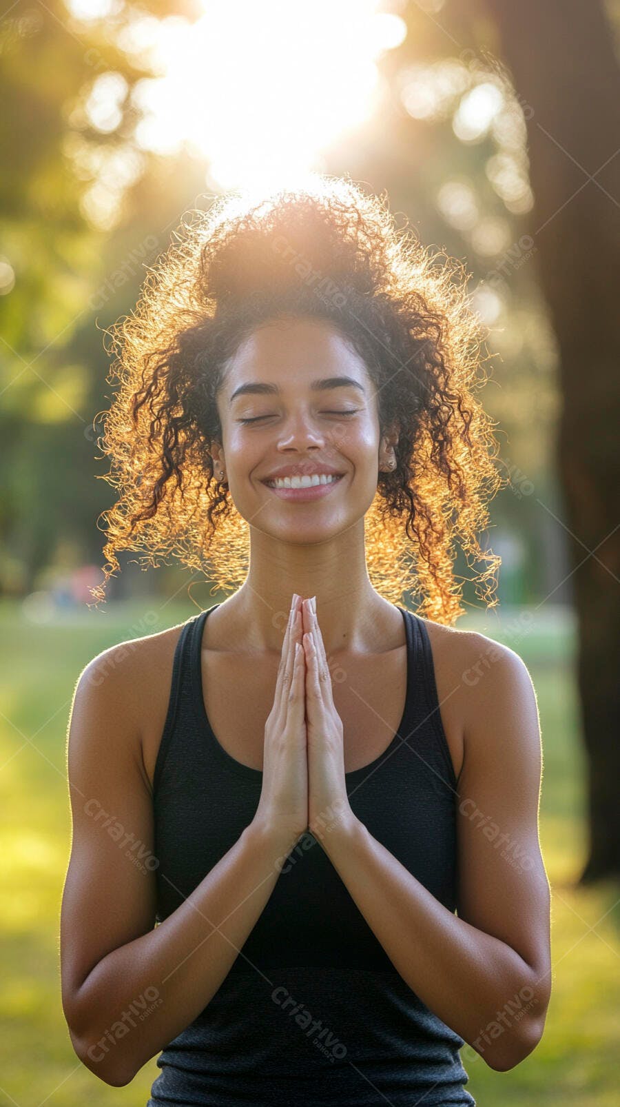 Mulher jovem sorrindo com mãos em oração no parque à luz dourada do entardecer