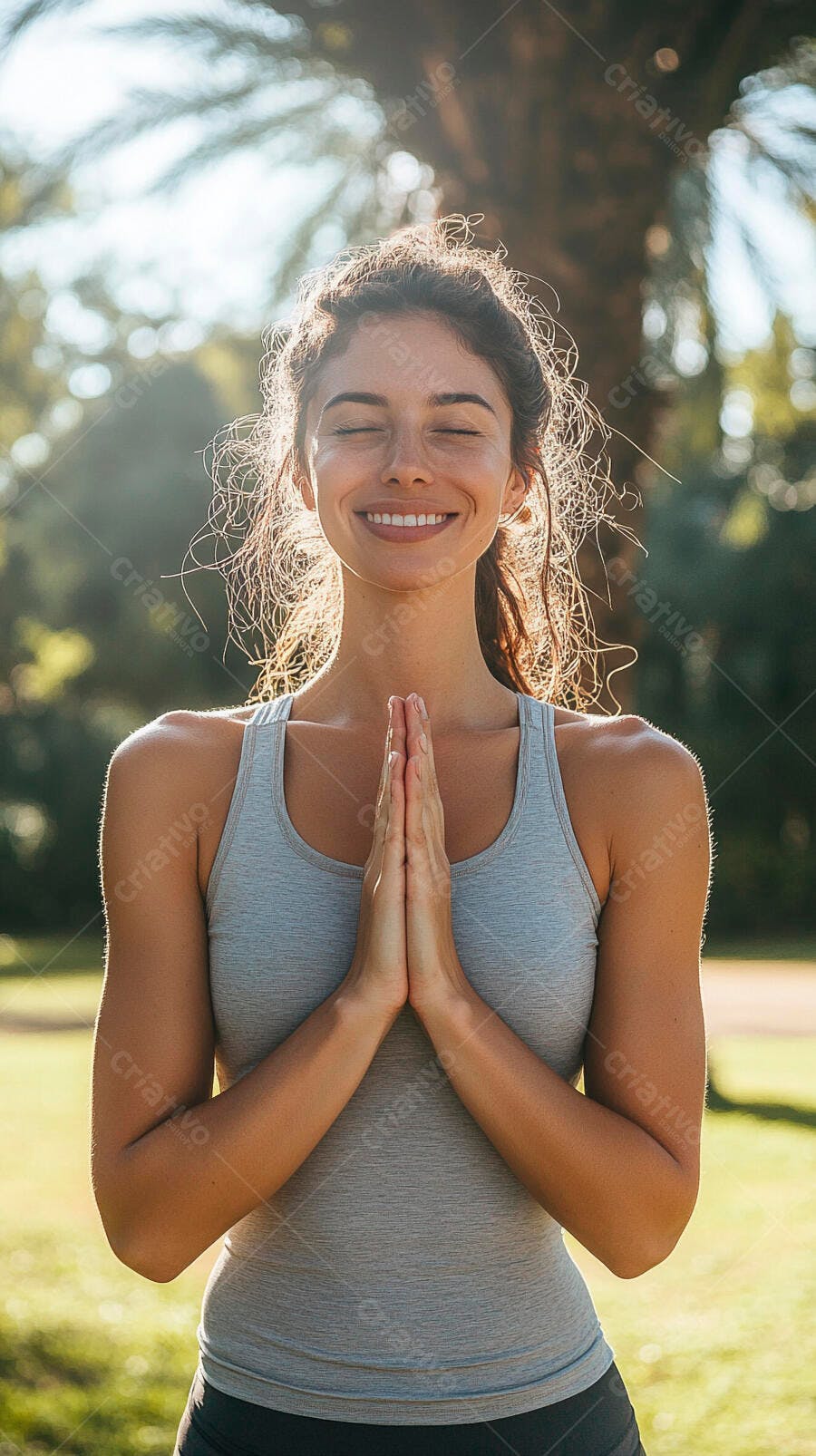 Mulher fitness de cabelo castanho meditando sorrindo em parque ensolarado