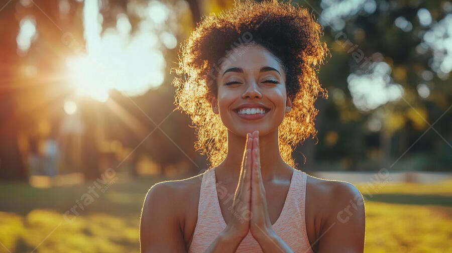 Mulher negra sorrindo meditando ao sol em pose de ioga no parque