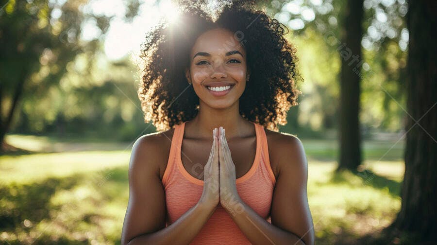 Mulher negra feliz cabelo cacheado sorrindo mãos namaste em parque verde ensolarado