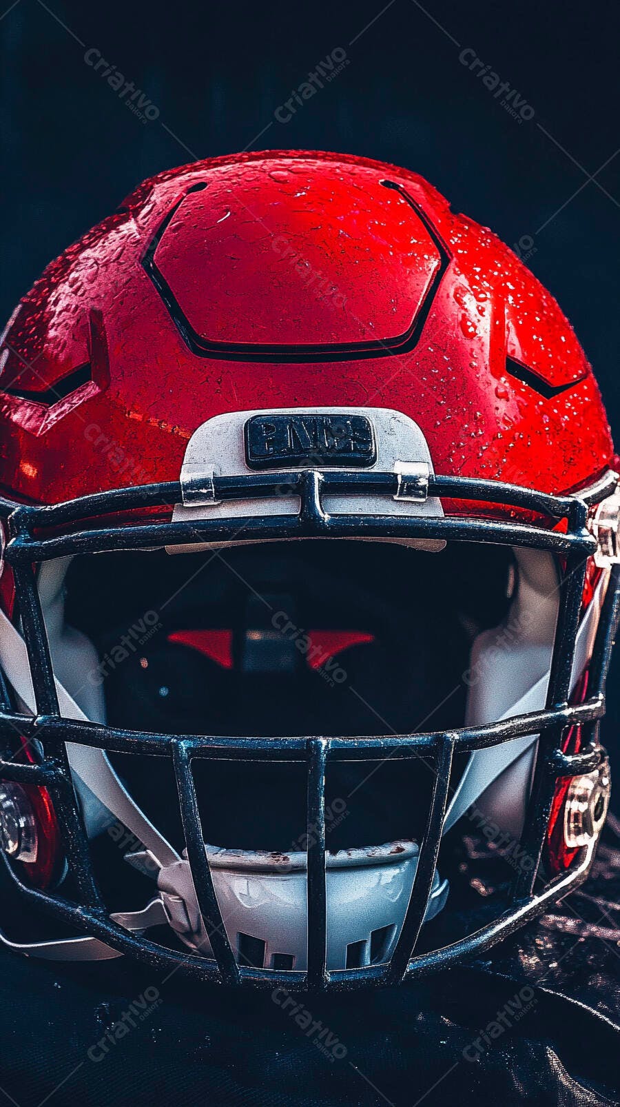 Capacete de futebol americano vermelho com gotas de água em campo escuro