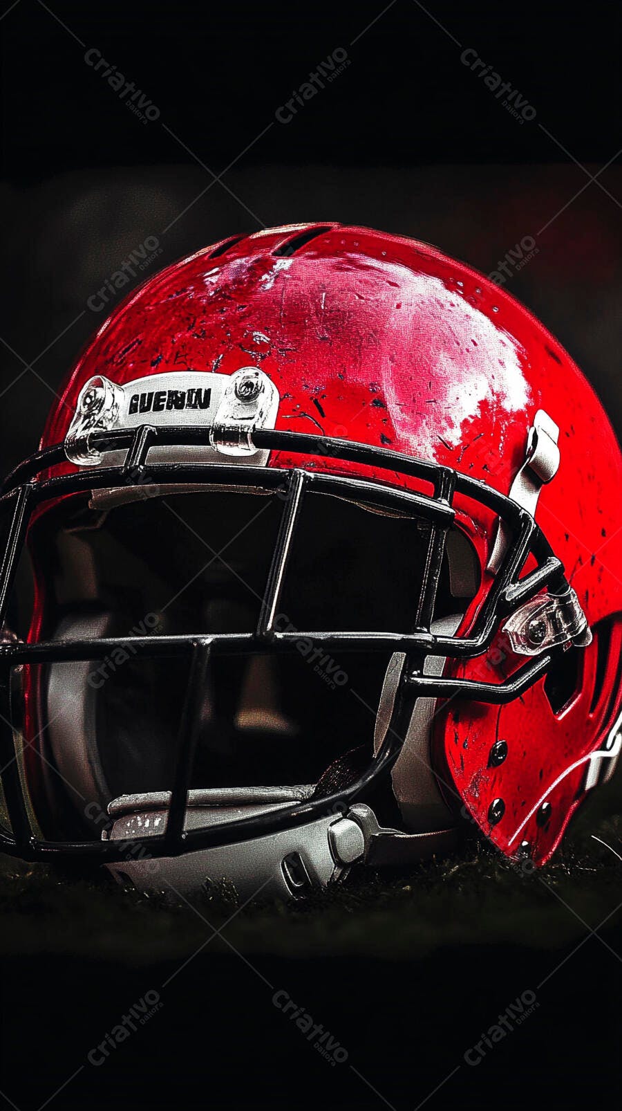 Capacete de futebol americano vermelho com máscara preta sobre grama escura