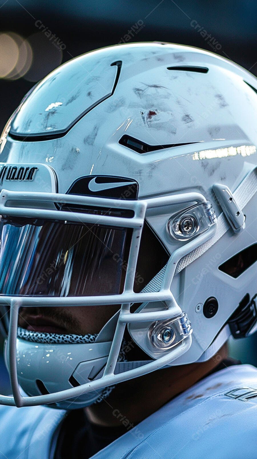 Jogador de futebol americano com capacete branco riscado e visor escuro em campo