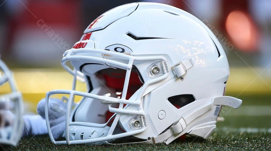 Capacete de futebol americano branco com detalhes vermelhos em campo verde