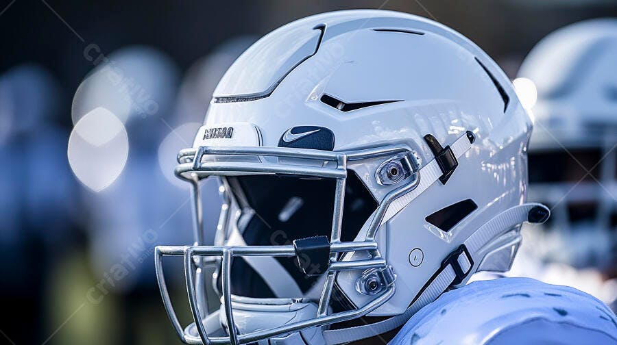 Capacete de futebol americano branco com grade metálica em campo difuso