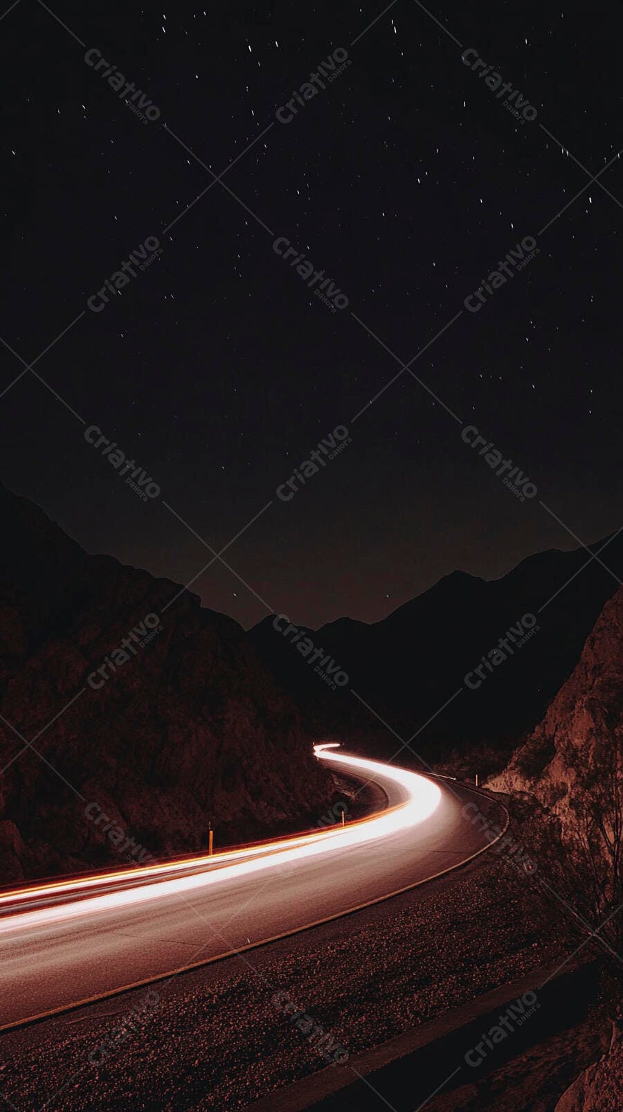 Estrada noturna sinuosa com rastro de luz de carro e céu estrelado