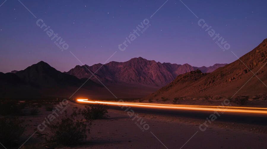 Trilha de luz laranja de carro em estrada de deserto montanhoso à noite