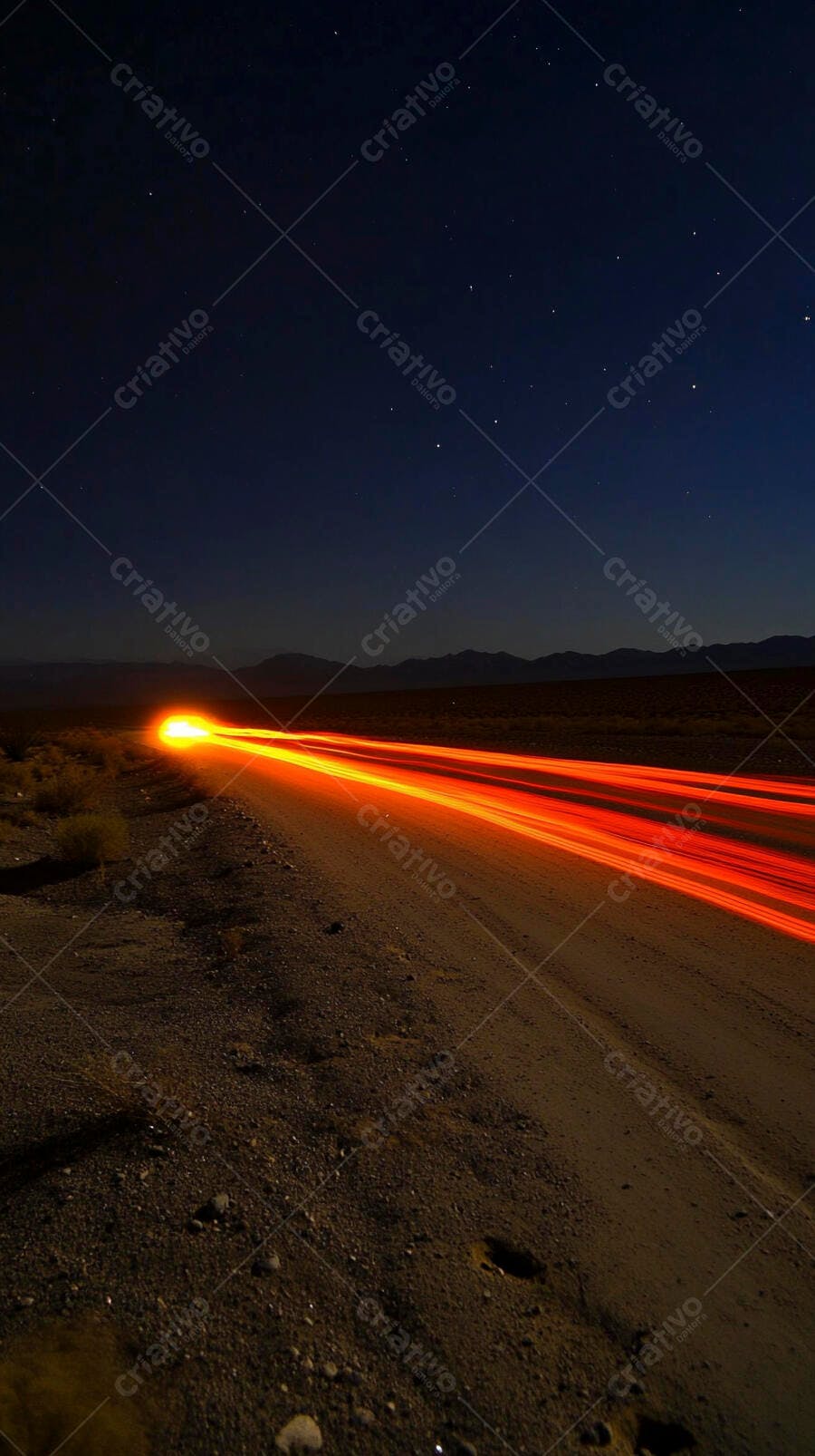 Luzes de carro em trilhas laranja na estrada de terra no deserto à noite