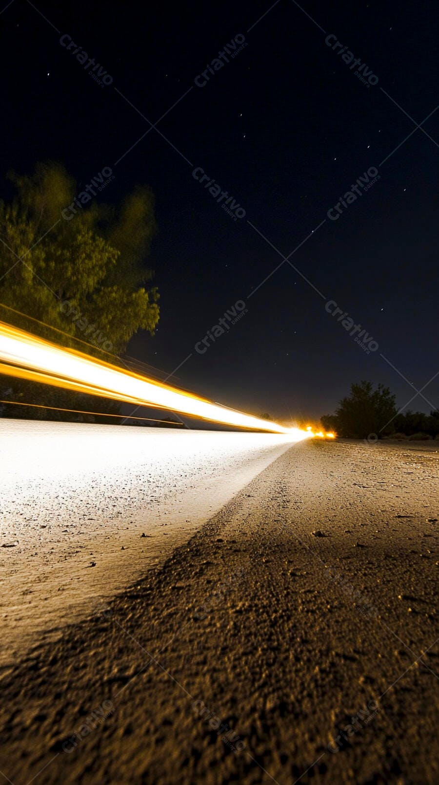 Estrada noturna com rastros de luz de veículos em movimento sob céu estrelado