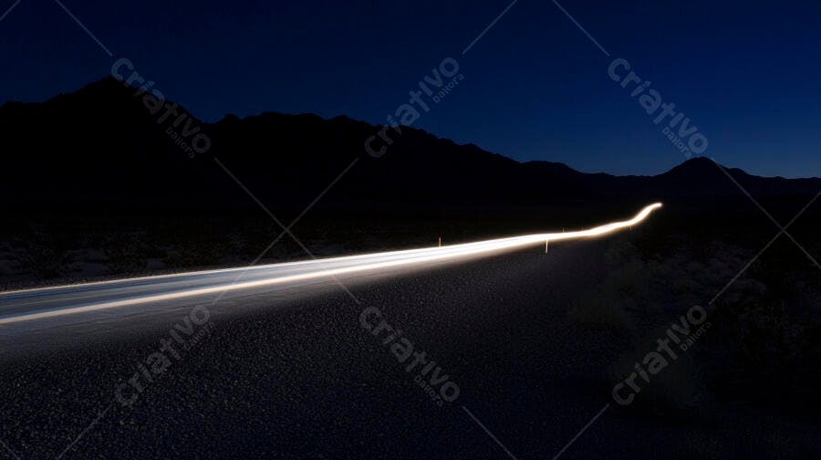 Estrada deserta noturna com rastros de luz de faróis e montanhas