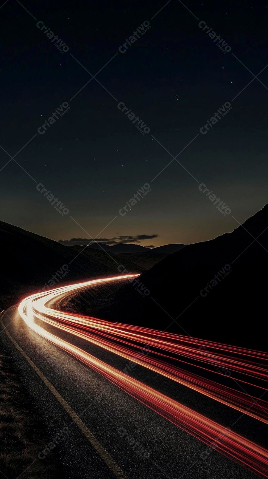 Estrada sinuosa com rastros de luz vermelhos e brancos entre montanhas à noite