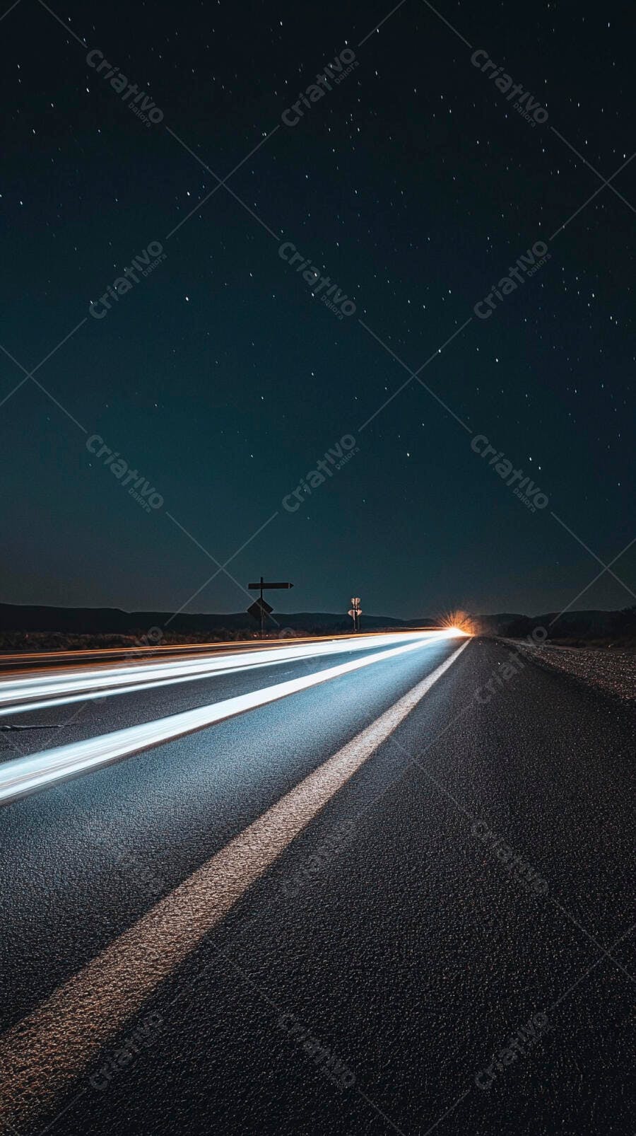 Estrada deserta à noite com rastros de luz de carros sob céu estrelado
