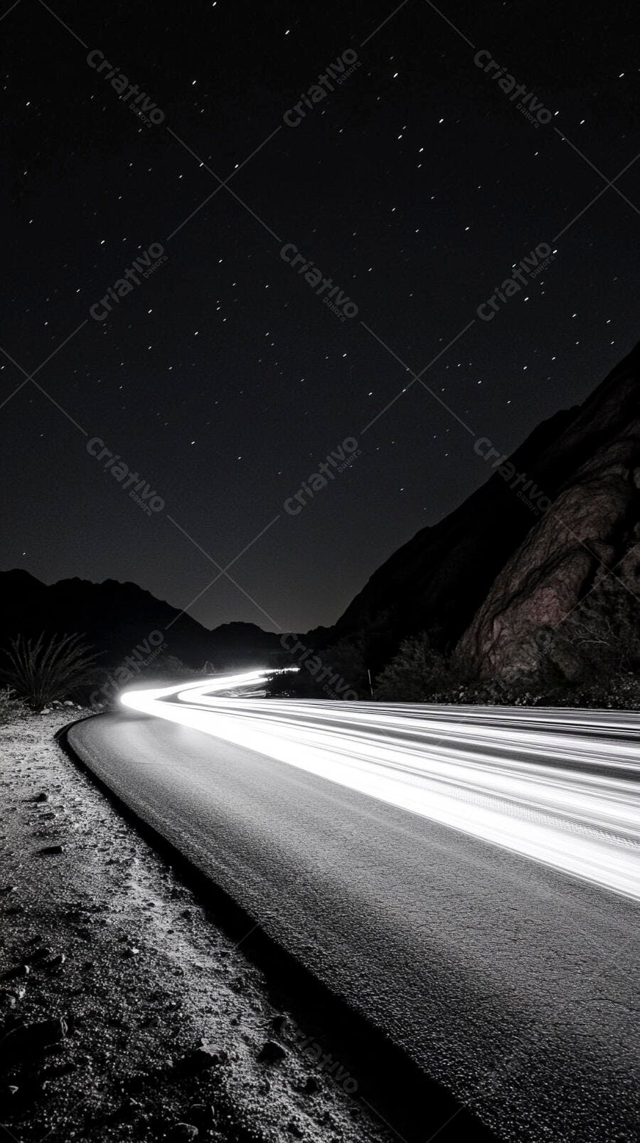 Estrada sinuosa à noite com rastros de luz de carros sob céu estrelado