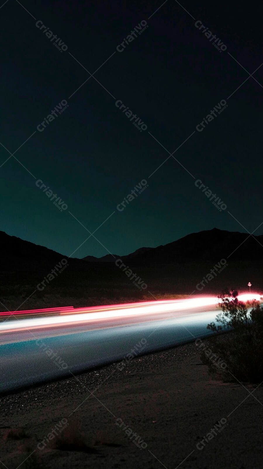 Carros na estrada deserta à noite com rastros de luz e montanhas