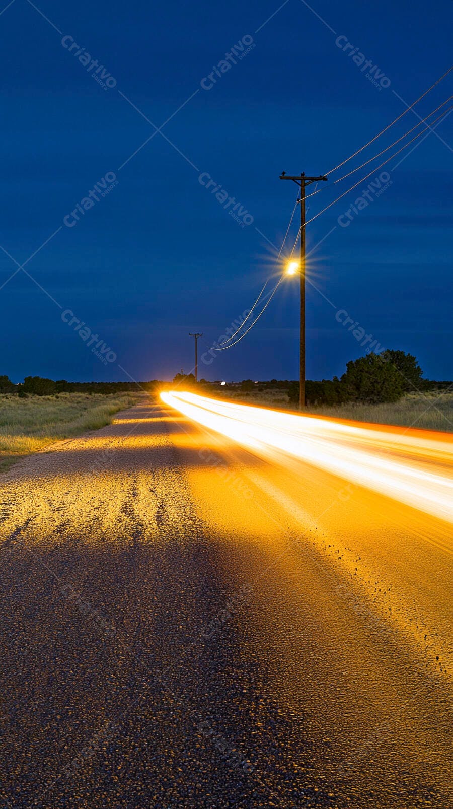 Rastros de luz de carro em estrada rural à noite com postes de energia