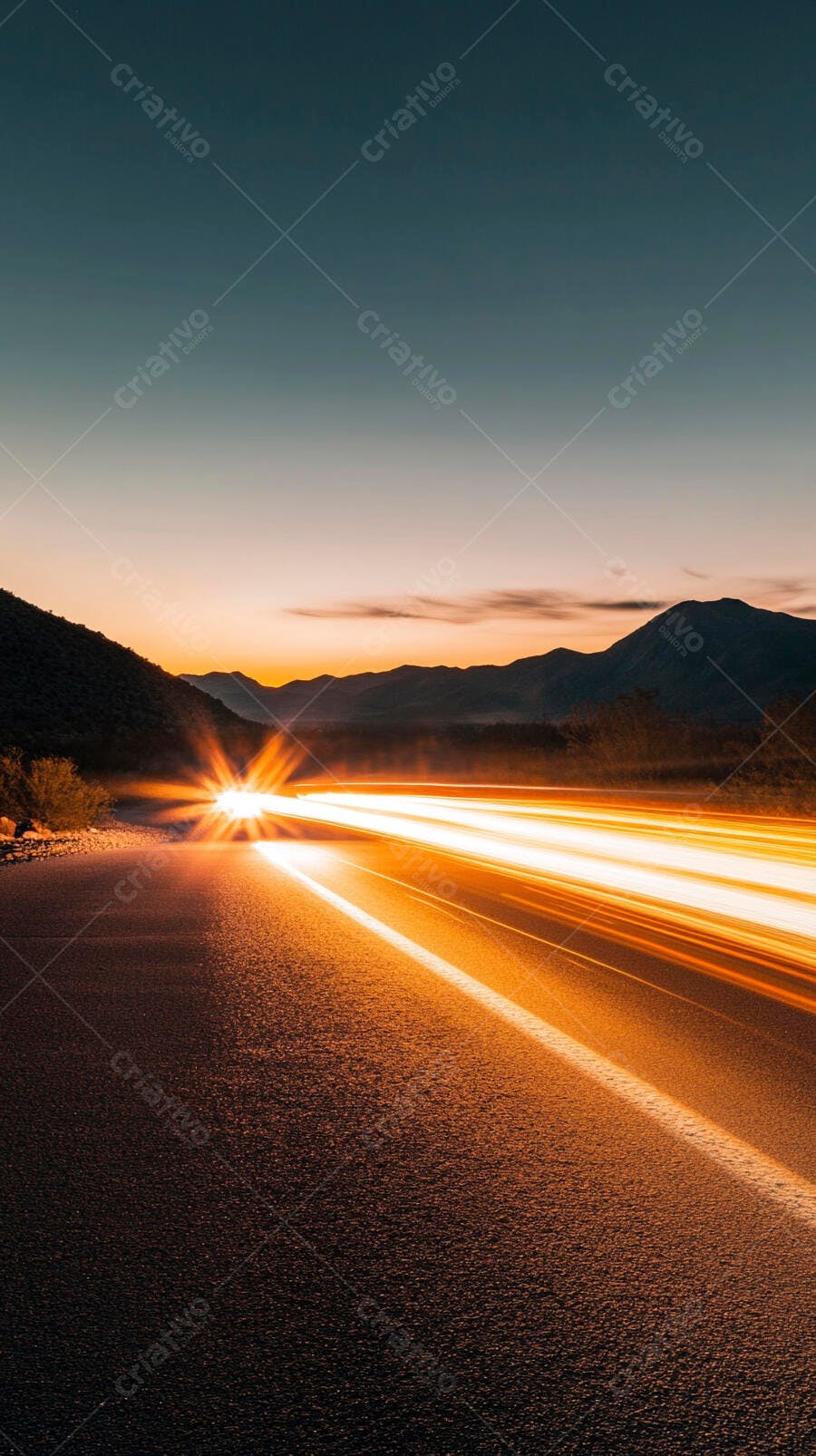 Rastros de luz em estrada deserta ao entardecer com montanhas