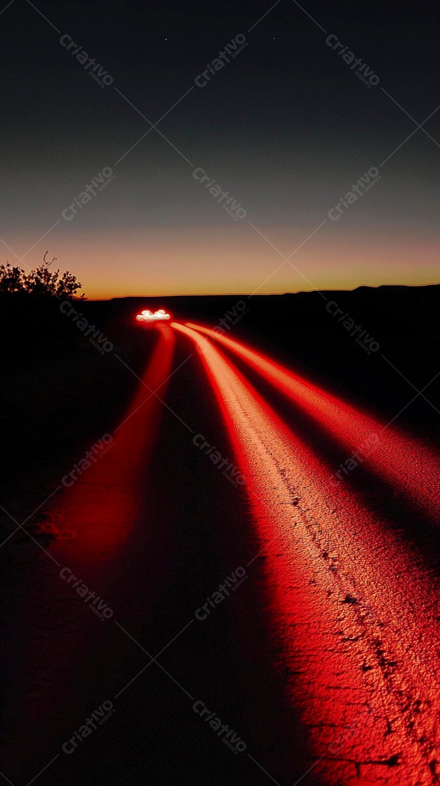 Carro com feixes de luz vermelha em estrada de terra ao entardecer