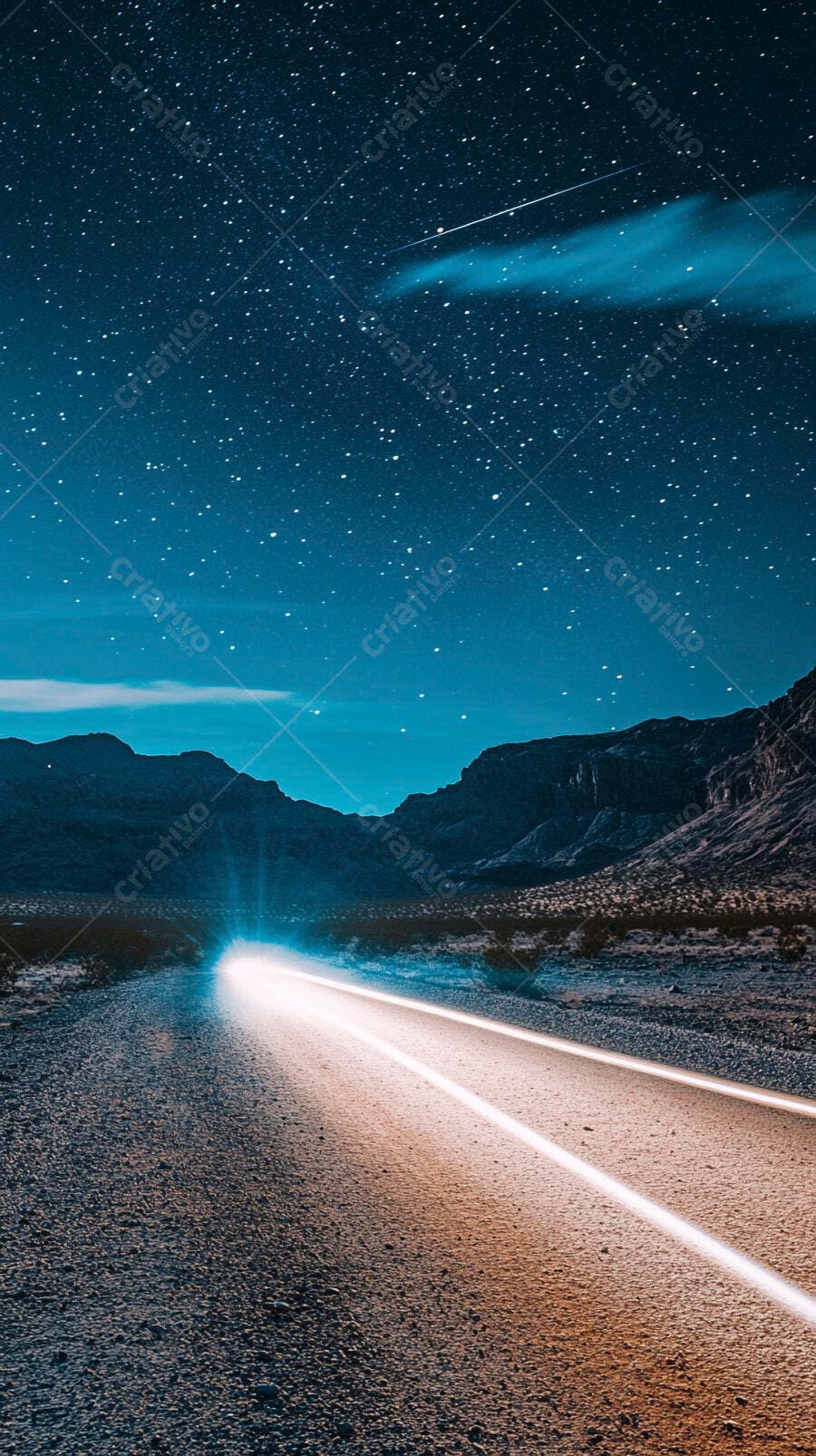 Estrada noturna iluminada por faróis sob céu estrelado e montanhas no deserto